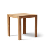 Vierkante tafel met ultra-dun tafelblad en verzonken poten van massief eikenhout. Subtiele schaduwlijn tussen blad en frame zorgt voor een licht zwevend effect. Modulair ontwerp dat meerdere tafels naadloos in een rij verbindt. Robuust en elegant, perfect voor dagelijks gebruik in moderne interieurs.