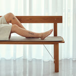 Person sitting on a wooden bench with white curtains in the background