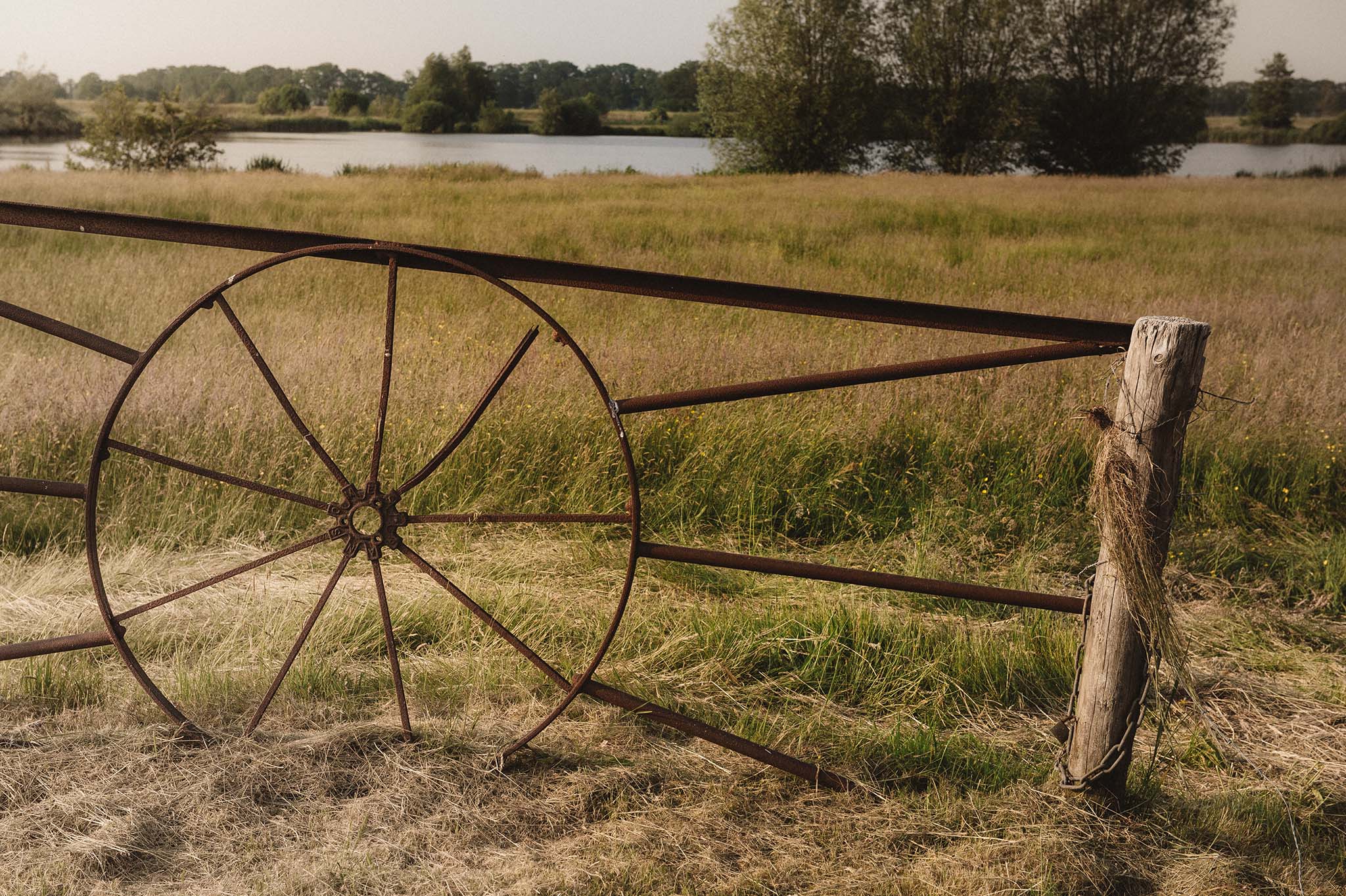 Rustiek hek in een groen landschap met uitzicht op de Vecht. 