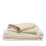 By Mölle's wheat linen duvet cover, crafted from 100% pre-washed European flax linen, features a natural chambray weave blending warm beige and off-white tones. The breathable and hypoallergenic fabric offers year-round comfort and is available with either wooden buttons or a tuck-in flap closure