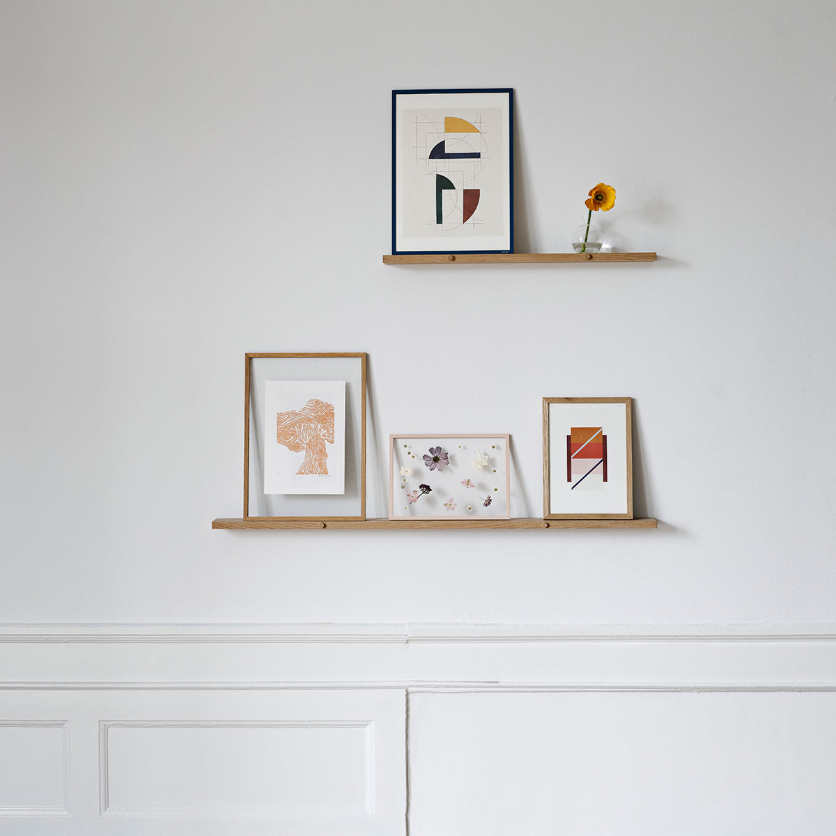 lijstjes en kleine kunstwerkjes op een gallery shelf aan een witte muur