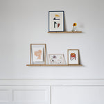 lijstjes en kleine kunstwerkjes op een gallery shelf aan een witte muur